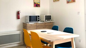 En spiseplads med et bord, stole, en hængende lampe og vægmonteret udstyr.