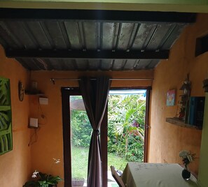 Ein Zimmer mit rustikalem Holzbalken-Unterzug, einem fenster mit Vorhängen, einem Bett, einem kleinen Tisch und einem Blumentopf.