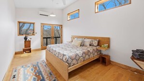Ein Schlafzimmer mit einem hölzernen Bett, einem Deckenventilator, einem Fenster mit Aussicht und einer eingebauten Ablage.