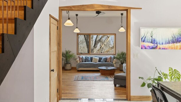 Ein modernes Interieur mit einer Treppe, einem Wohnbereich inklusive Sofa, Couchtisch und einem Gemälde.