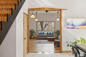 Ein modernes Interieur mit einer Treppe, einem Wohnbereich inklusive Sofa, Couchtisch und einem Gemälde.
