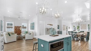 A spacious kitchen with a central island, teal cabinetry, and modern pendant lighting. - Windsong! New! Sleeps 19! Beach! (Destin)