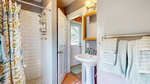 A bathroom with a shower, a sink, and a towel rack.