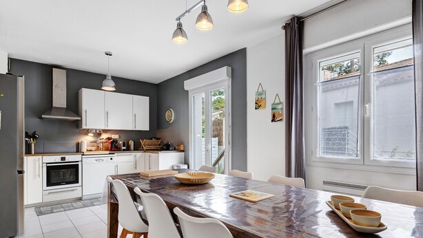 A modern kitchen with white cabinets, a large island, and pendant lighting. - Villa des Mahonies just 200m from the beach (La Tranche-sur-Mer)