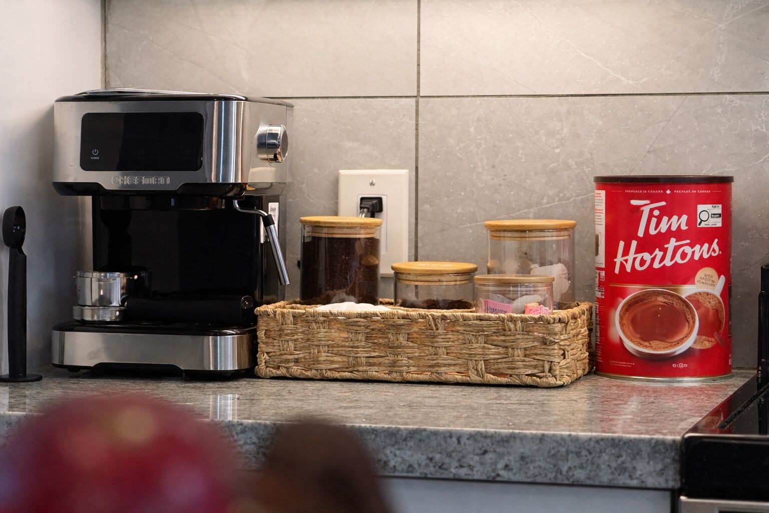 Eine Küche mit Kaffeemaschine, Gläsern und einer Kaffeedose von Tim Hortons.