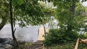 A wooden dock leading to a calm lake, surrounded by trees and rocks. - River Retreat- Hot tub/Games/BBQ/Bonfire/Sleeps 14 (Tweed)