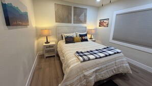 A bedroom with a bed, two bedside tables with lamps, a ceiling fan, and artwork on the walls. - Welcome to the Sundancer @ the Little Littleton Village (Littleton)