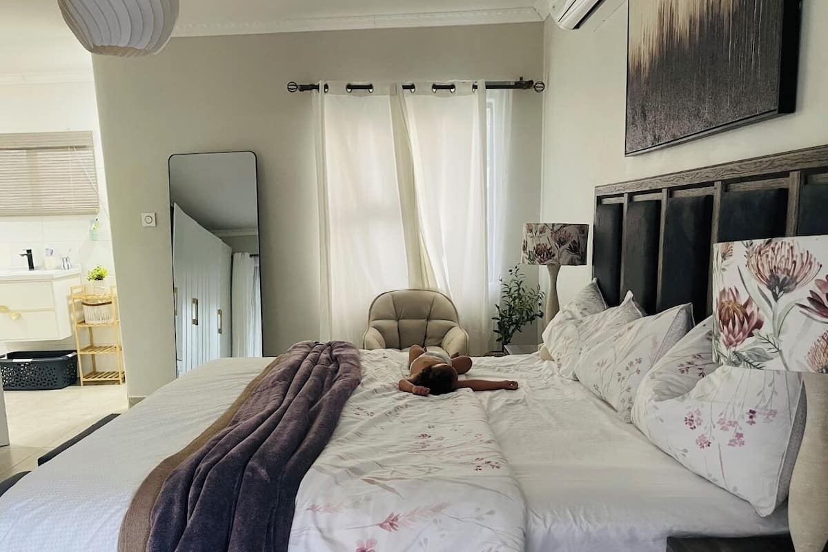 Un dormitorio con una cama grande, un cabecero con motivos florales, una silla y un espejo en la pared.