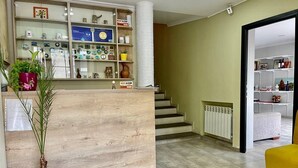 Ein Empfangsbereich mit einem Holzbüro, einer Zimmerpflanze und einer Treppe zu einer oberen Etage.