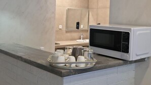 Eine moderne Küche mit einer weißen Mikrowelle, einer Kaffeetasse-Unterlage und einer Wand mit Backsteinoptik.