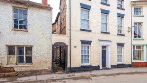 A row of traditional buildings with a mix of architectural styles, including a white building with a black gate and a beige building with blue trim. - Charming Grade II Listed Apartment | Sleeps 4 (Wem)