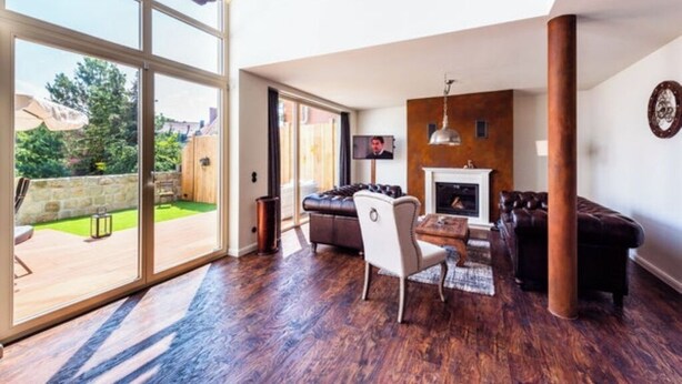 A spacious living room with a fireplace, a large window, and a view of the backyard.