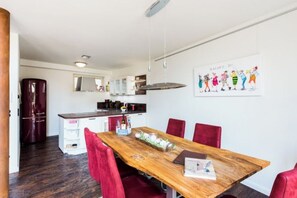 Eine moderne Küche mit einem Holztisch und roten Stühlen, einem Kühlschrank und einem Essbereich mit einem Poster an der Wand.