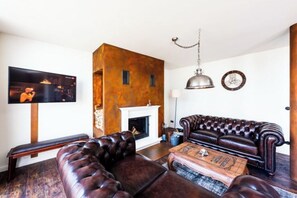 Ein Wohnzimmer mit Kamin, einer Ledersofa und einem an der Wand befestigten Fernseher.