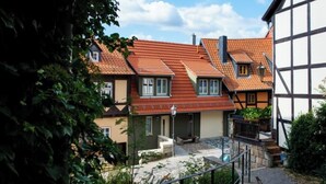 A traditional European-style building with a sloped roof, a stone pathway, and a small garden area.