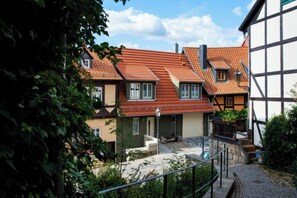 Ein Gebäude im traditionellen europäischen Stil mit einem geneigten Dach, einem Steinweg und einem kleinen Garten.