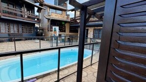 Uma área de piscina com vista desobstruída para um edifício com varandas e chão revestido de azulejos.