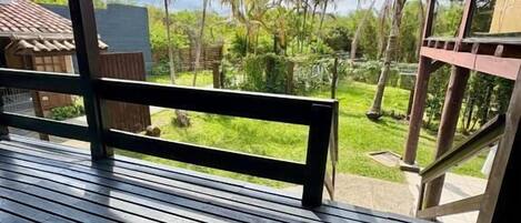 A wooden deck with a view of a lush garden and palm trees.