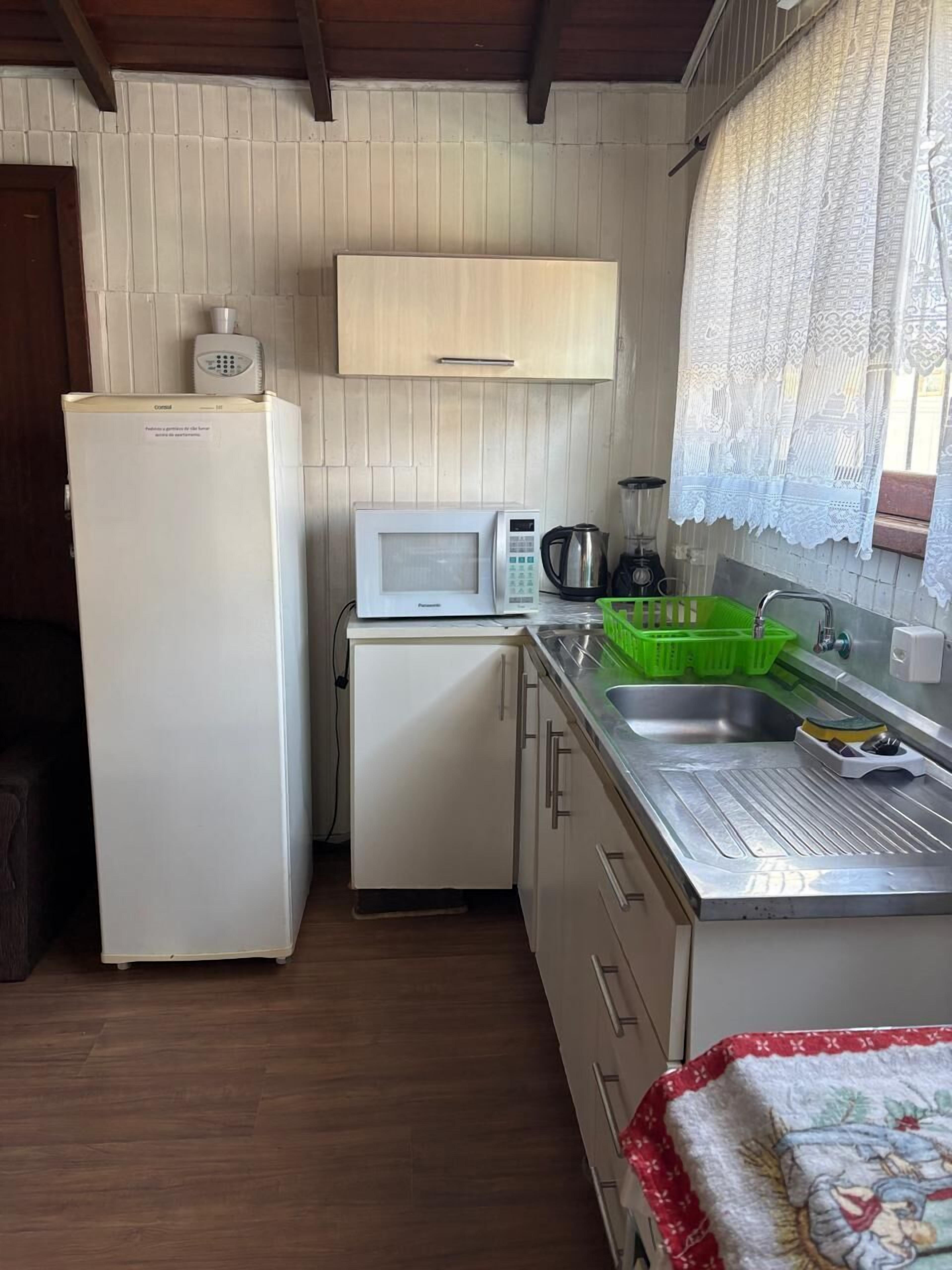 A compact kitchen with a refrigerator, microwave, sink, and a small countertop.