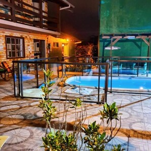 Un área de piscina con barandilla de vidrio, un edificio de ladrillo y un letrero que dice 'LAZER'.