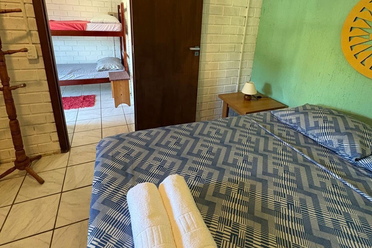 A room with a bed, a wooden door, a small table, and a wall with a circular design.