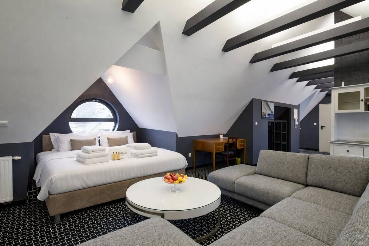 A modern, compact room with a bed, a round coffee table, and a sofa.
