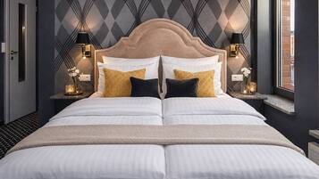 A double bed with a tufted headboard, two bedside tables with lamps, and a patterned wall.
