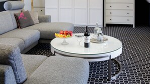 A modern living room with a grey sofa, a glass coffee table with a bottle and glasses, and a fruit bowl. - Cocorico Boutique Stay Adults Only (Szczecin)