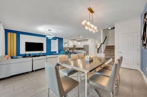 Un salon moderne avec un téléviseur, un canapé et un coin repas.
