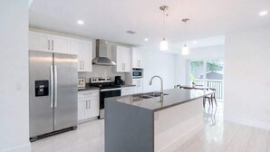 A modern kitchen with stainless steel appliances, a central island with a sink, and pendant lighting.