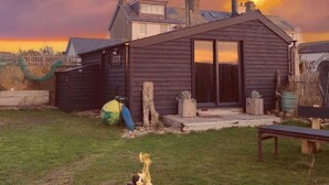 Una cabaña rústica con chimenea, una fogata y una terraza de madera.