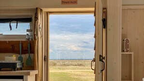 Una habitación con detalles de madera, una cama, una silla y vistas a aerogeneradores al exterior.