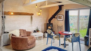 Interior acogedor de una cabaña con techo de madera, chimenea, sofá y zona de comedor.