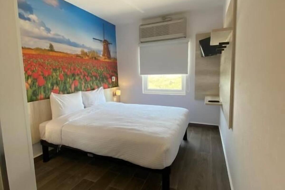 Camera da letto con un letto, una finestra, un condizionatore d'aria e una TV a parete.