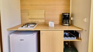 Pieni, käytännöllinen keittokomero, jossa on kaasuliesi, kahvinkeitin, jääkaappi ja kaasupullo.