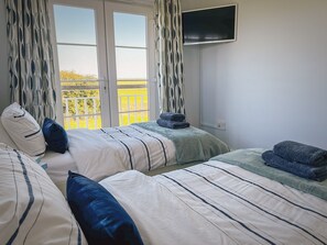 A hotel room with two beds, a TV mounted on the wall, and a balcony with a view of the countryside. - Marine House -  a cottage that sleeps 8 guests  in 4 bedrooms (Camber)