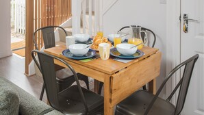 Uma sala de jantar com uma mesa de madeira, quatro cadeiras e uma escada.
