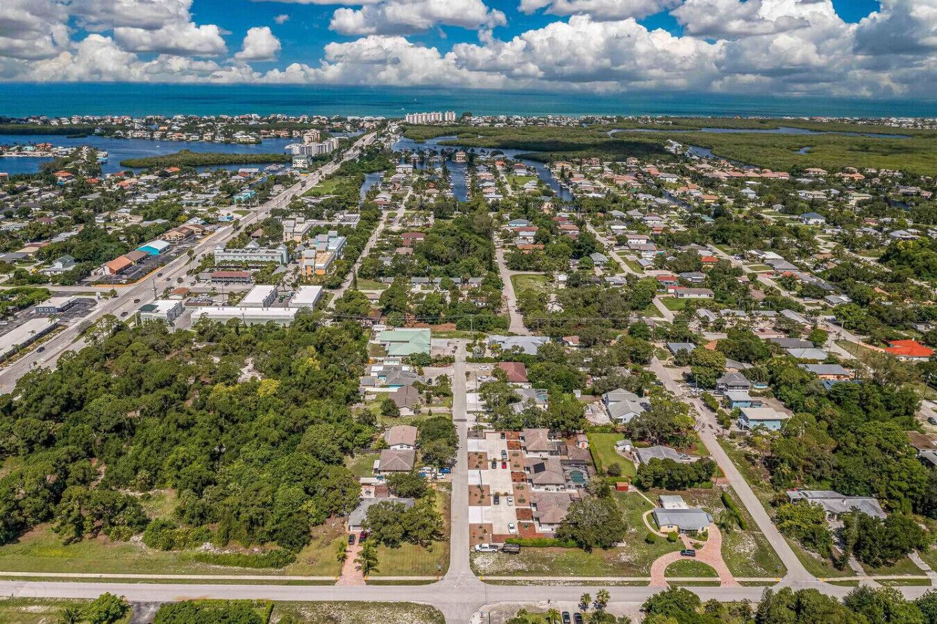 An aerial view of a residential area with houses, roads, and a distant body of water.