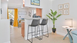 Une cuisine moderne avec un coin bar, une plante en pot et des tableaux encadrés au mur.
