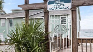 A wooden boardwalk leading to a building with a sign indicating a private boardwalk. - 1 bdrm sleeps 6 with hall bunks (Miramar Beach)