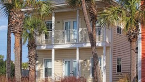 A two-story building with a balcony on the second floor, surrounded by palm trees. - 1 bdrm sleeps 6 with hall bunks (Miramar Beach)