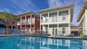 A poolside view of a hotel with a two-story building, a covered deck, and a clear blue sky. - 1 bdrm sleeps 6 with hall bunks (Miramar Beach)