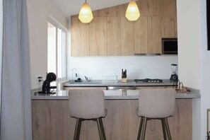 Une cuisine moderne avec des meubles en bois, un évier en acier inoxydable et deux tabourets de bar.
