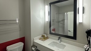 Ein modernes Badezimmer mit Toilette, Waschbecken, Spiegel, Handtuchhalter und Fön.