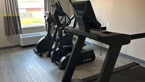 Un gimnasio equipado con cintas de correr, elípticas y una bicicleta estática.