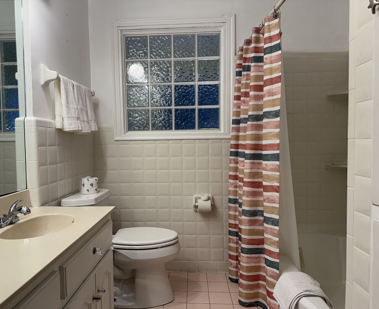 A bathroom with a toilet, sink, and window.