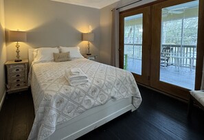 Een slaapkamer met een bed, twee nachtkastjes, een raam en uitzicht op een terras.