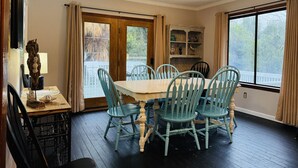A dining area with a table and chairs, a window with curtains, and a wooden cabinet. - The Fish Cottage - south beach, lots of amenities (Tybee Island)