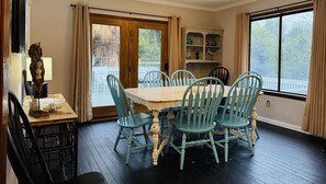 A dining area with a table and chairs, a window with curtains, and a wooden cabinet. - The Fish Cottage - south beach, lots of amenities (Tybee Island)