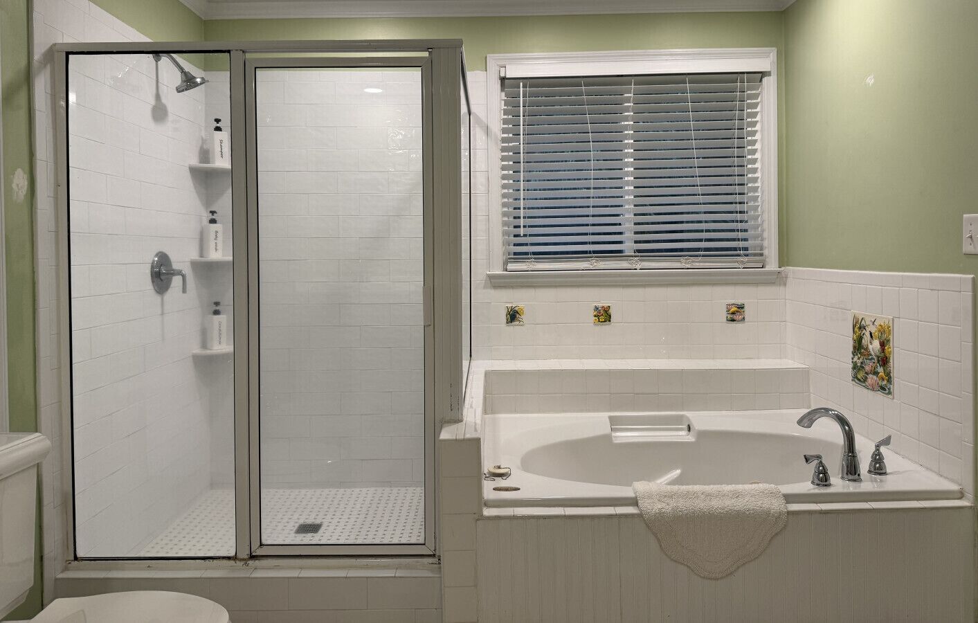 Un baño con cabina de ducha, bañera y ventana con persianas.